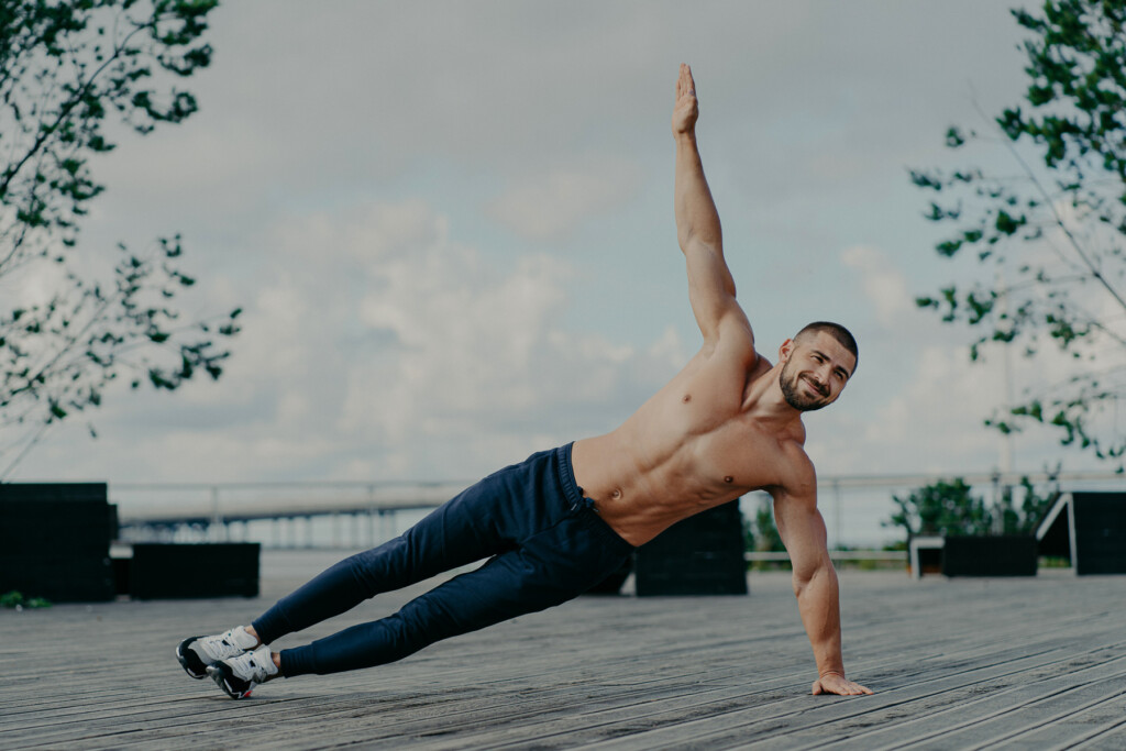 healthy-man-stands-in-abs-side-plank-and-raises-ar-2023-11-27-05-29-36-utc